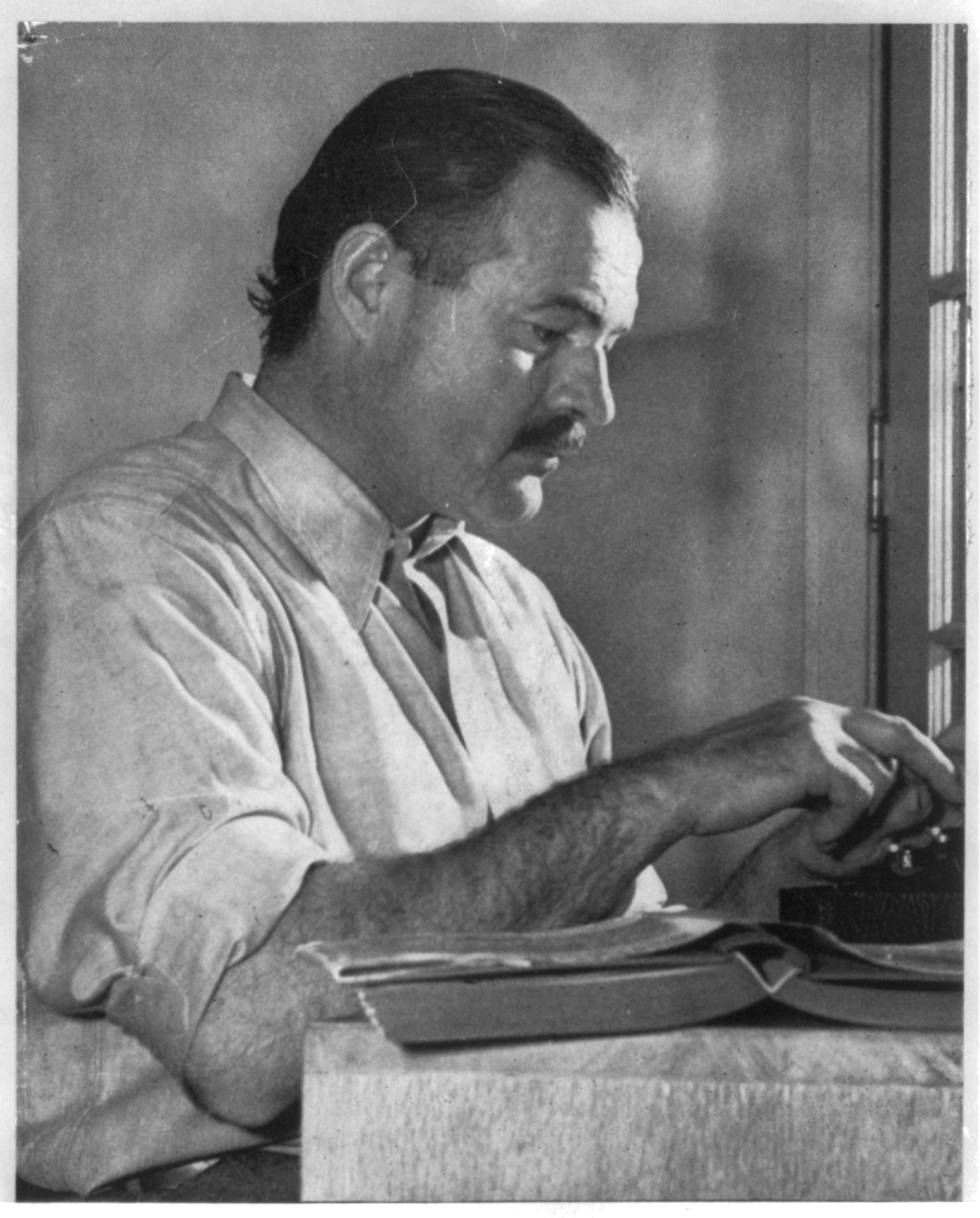 Ernest Hemingway seated at typewriter